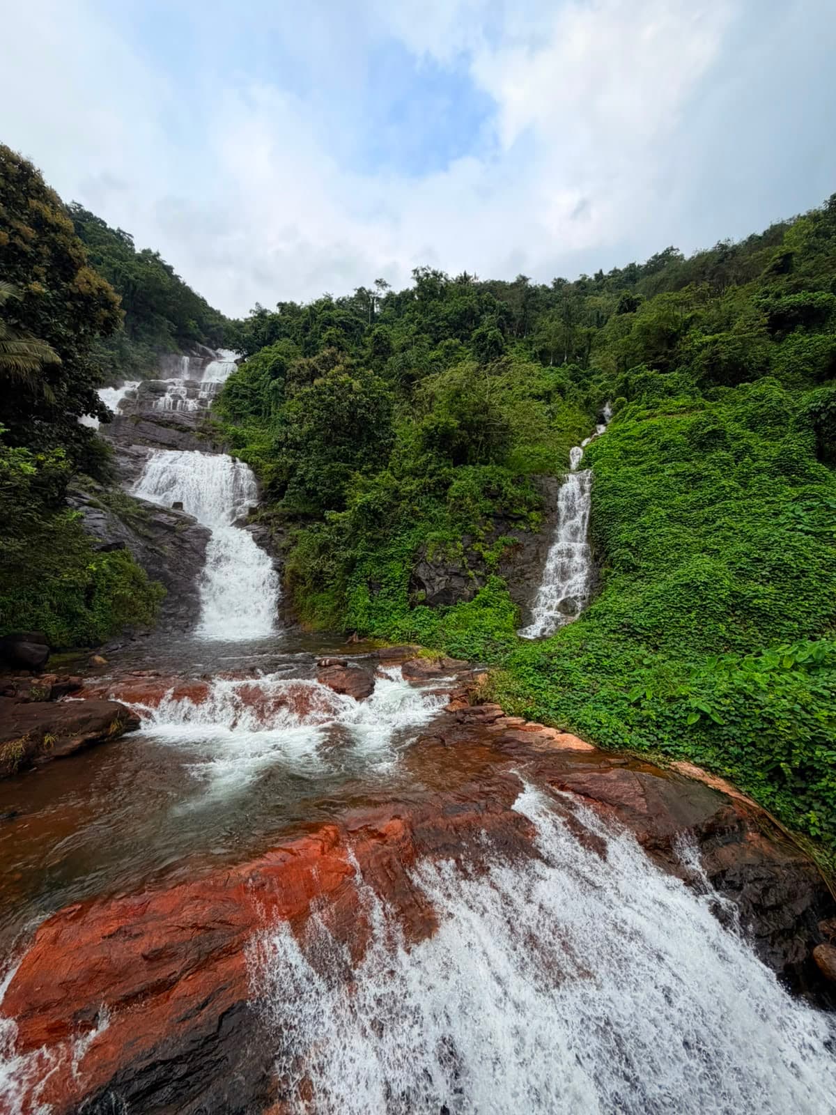 The two tiers of Vadakkemala Waterfall falling over red rock